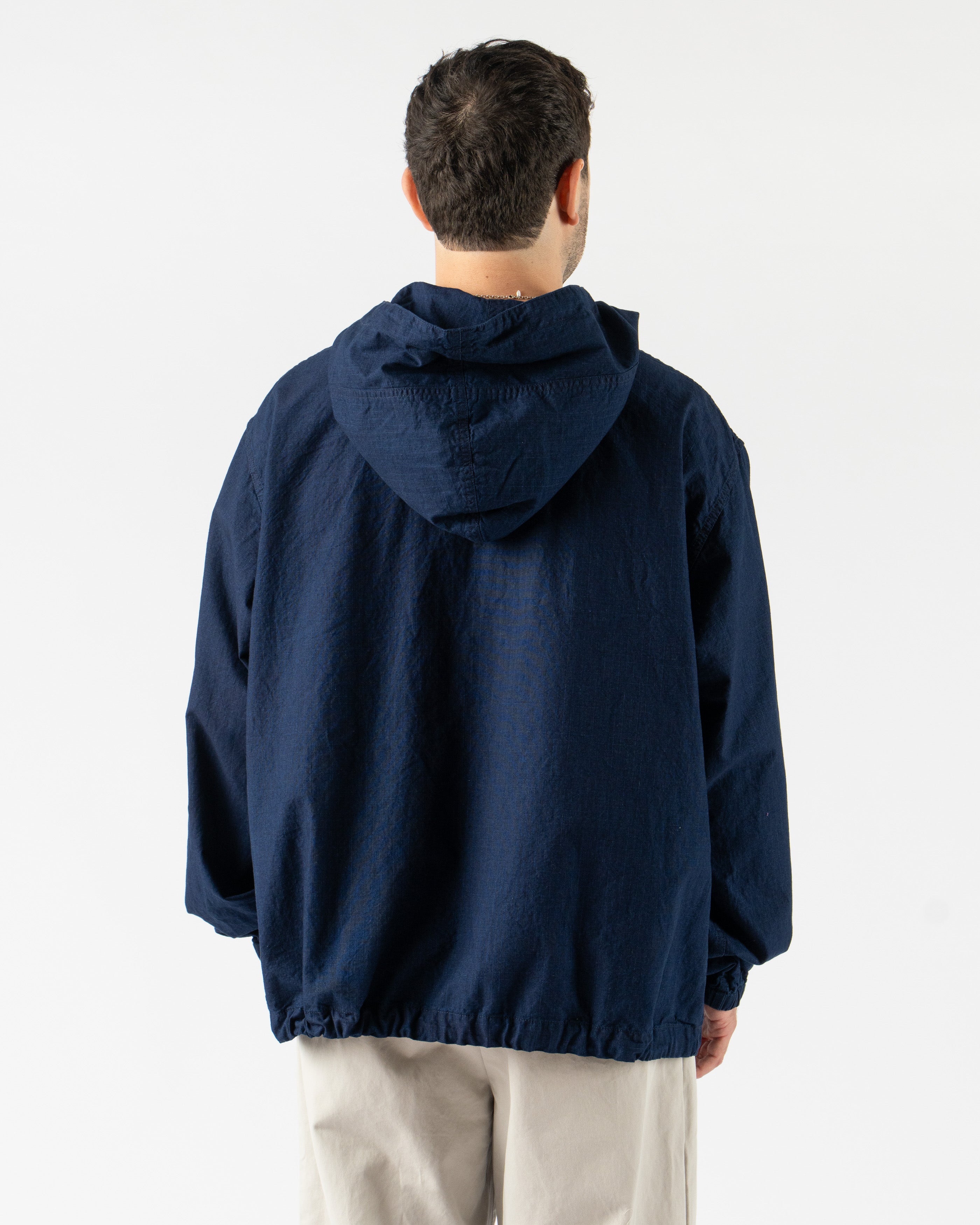 Beams Plus MIL Smock in Indigo Ripstop – military-inspired pullover smock crafted from durable indigo-dyed ripstop fabric, featuring a half-zip front, adjustable hood, large utility pockets, and a relaxed fit for functional everyday wear.