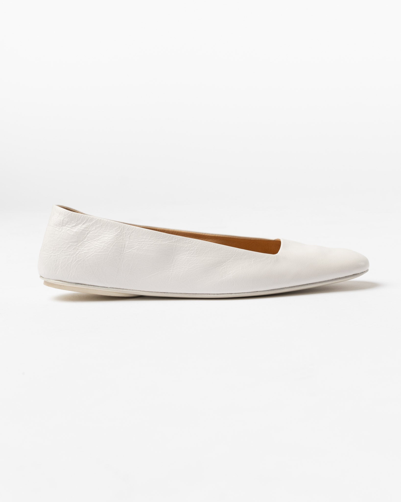 White flat shoe with a brown insole on a white background