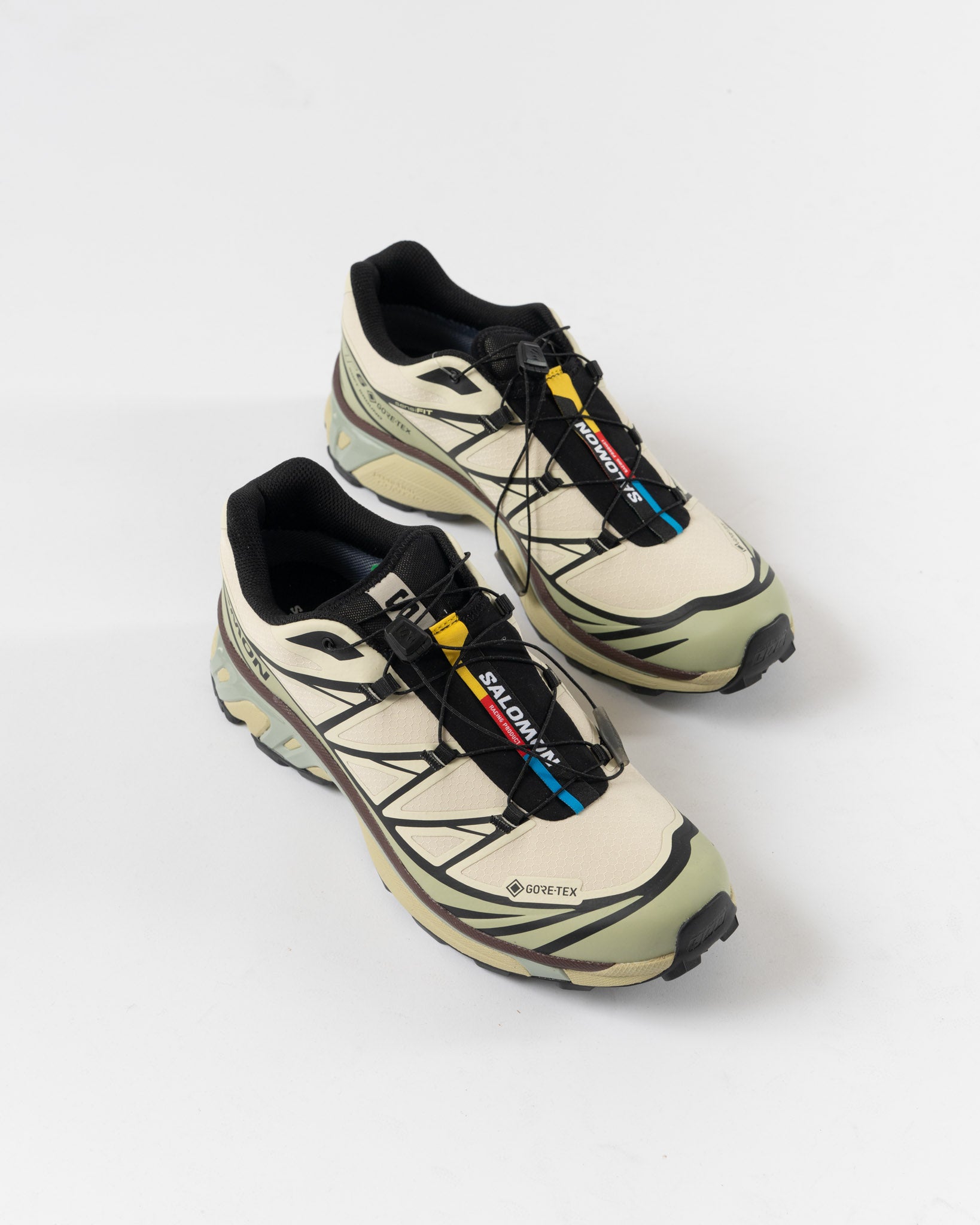 Pair of beige and black sneakers with brand logos on a white background