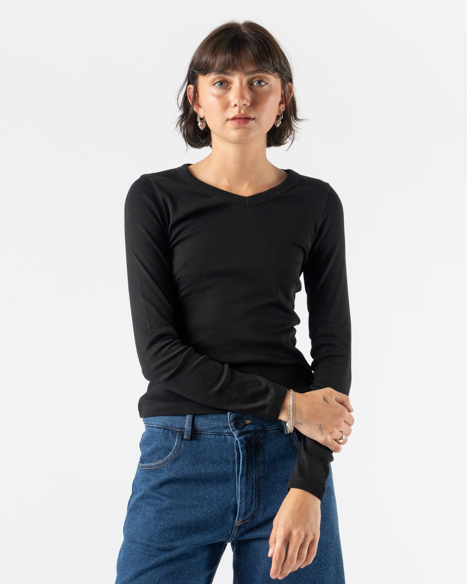 Person wearing a black long-sleeve shirt and blue jeans on a white background