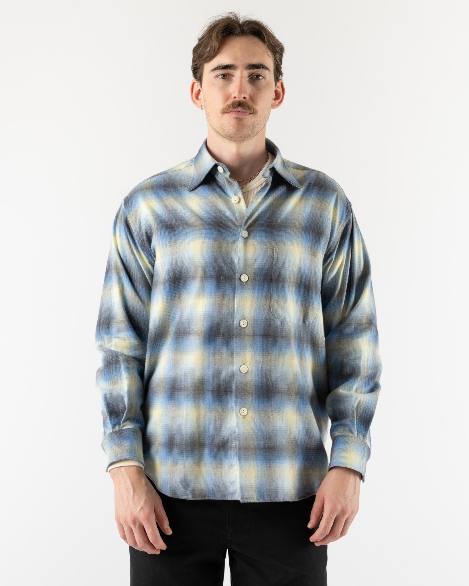 Man wearing a blue and yellow plaid shirt against a white background