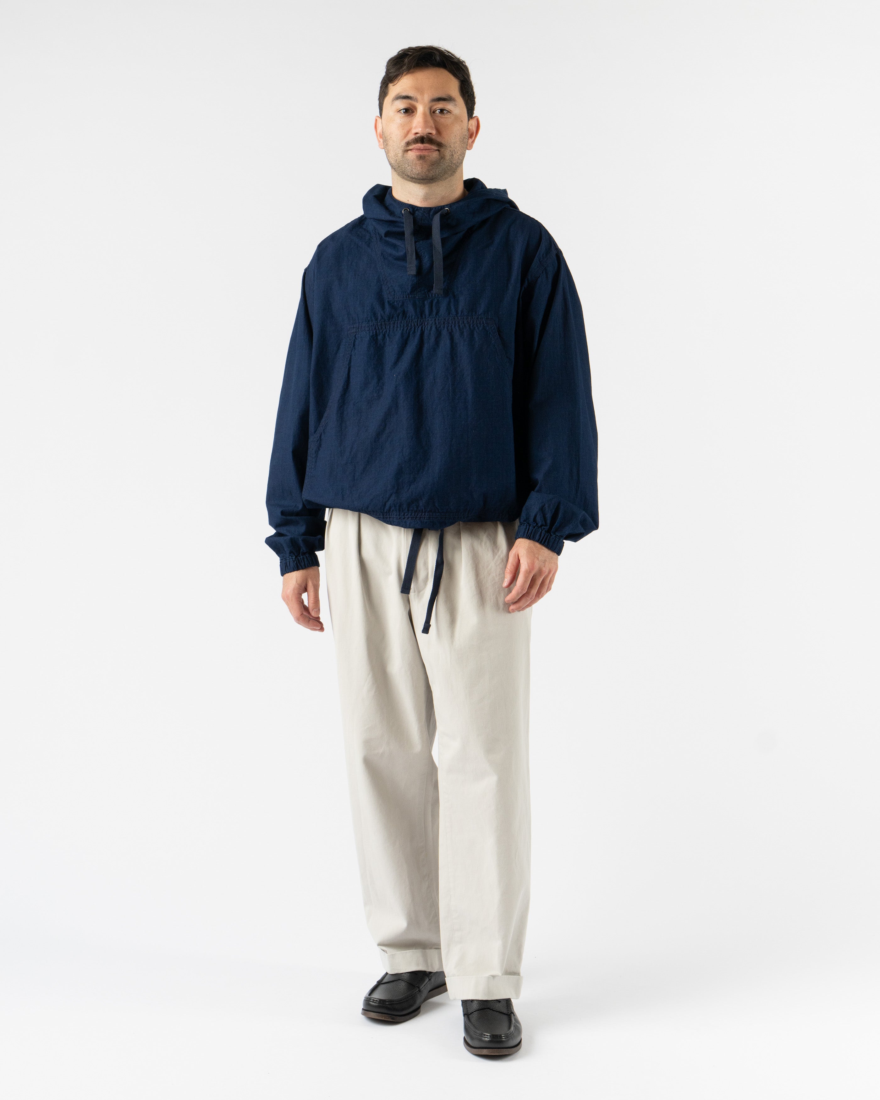  Beams Plus MIL Smock in Indigo Ripstop – military-inspired pullover smock crafted from durable indigo-dyed ripstop fabric, featuring a half-zip front, adjustable hood, large utility pockets, and a relaxed fit for functional everyday wear.