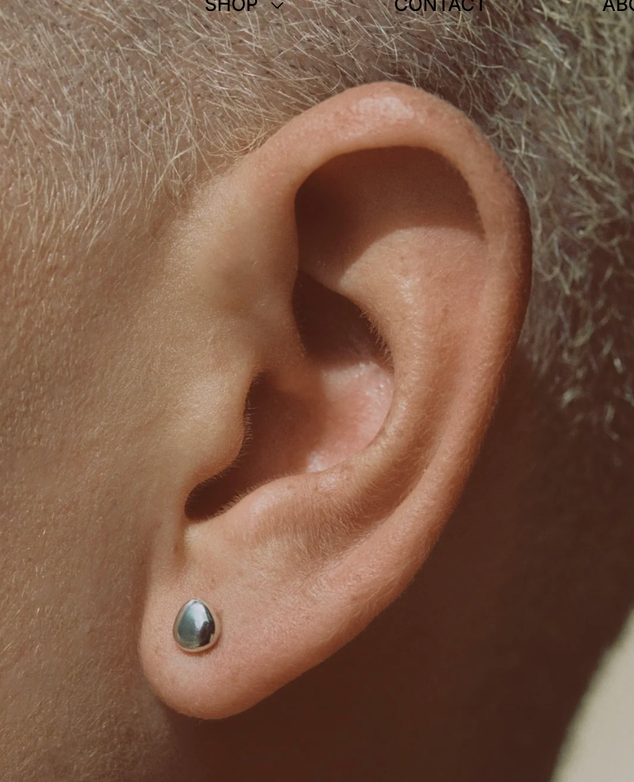 Close-up of an ear with a small earring on a neutral background