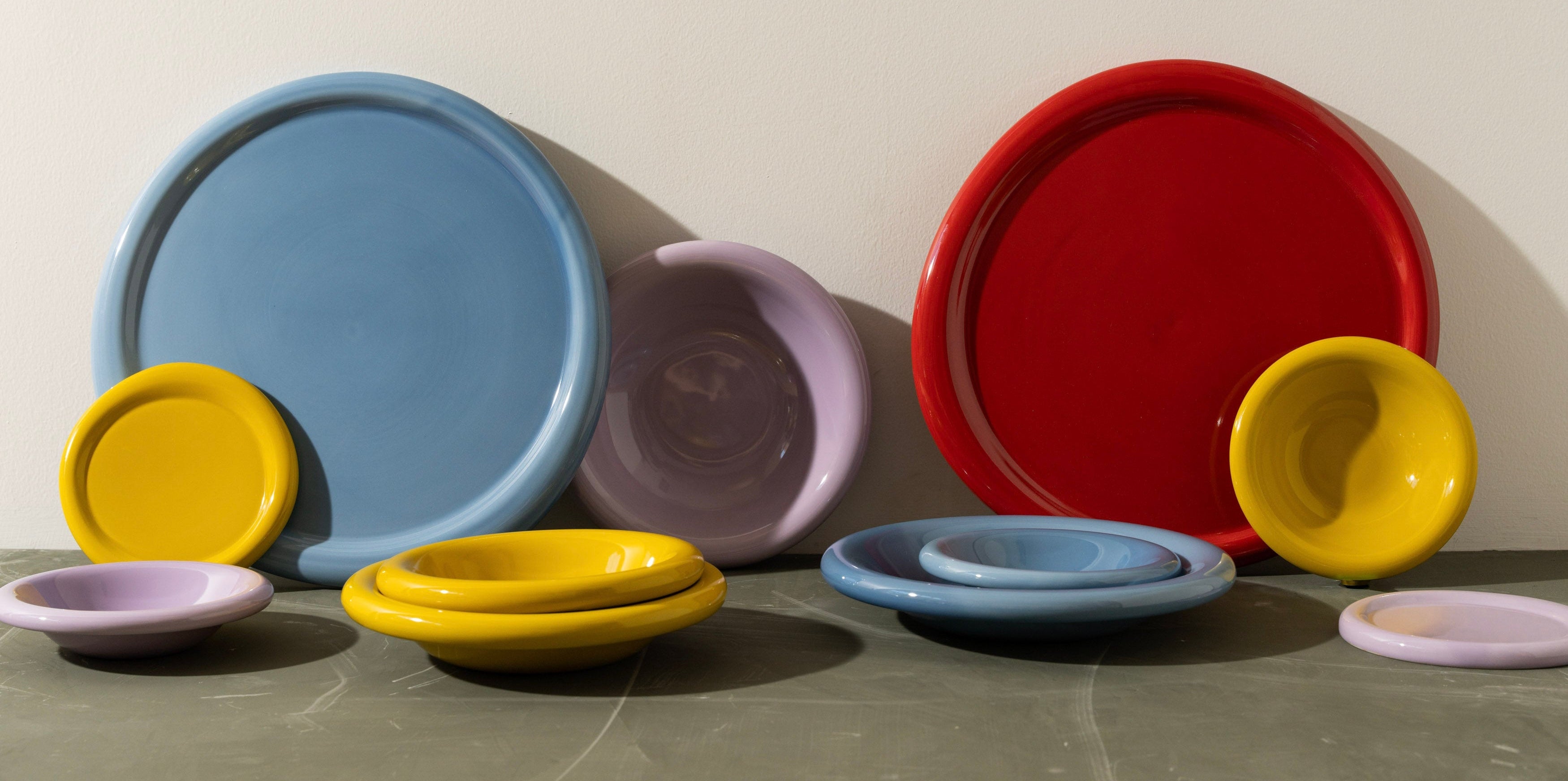 Set of colorful ceramic plates and bowls on a gray surface with a beige background
