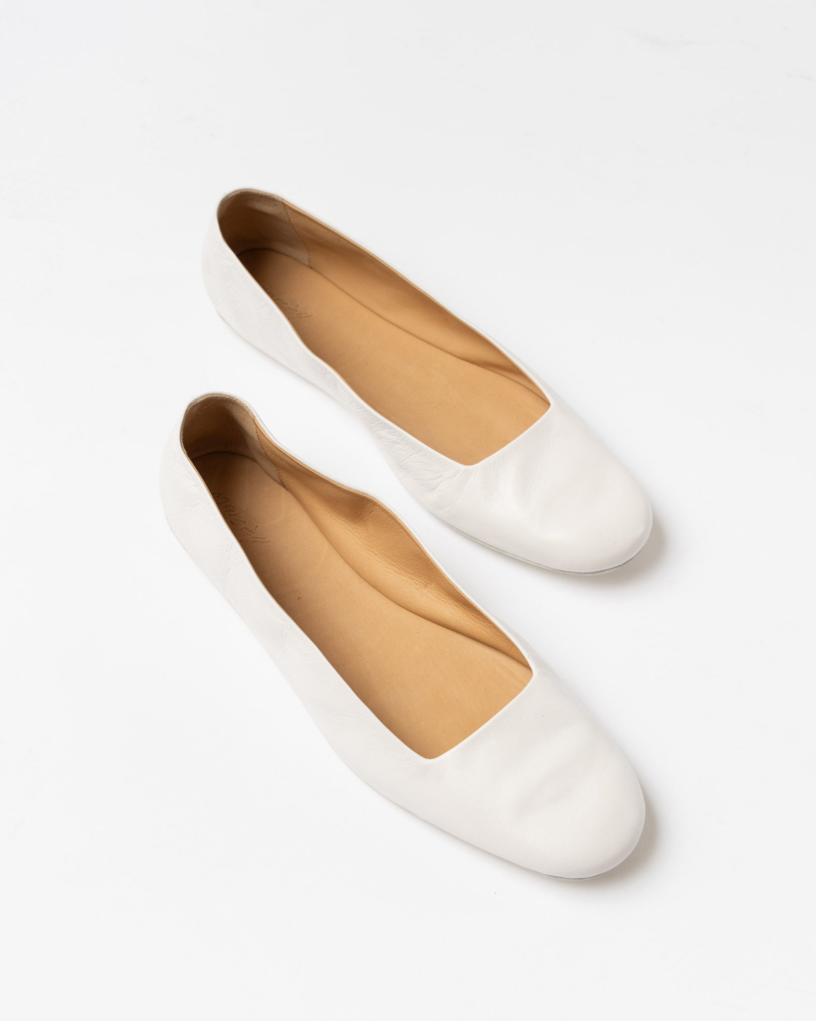 Pair of white flat shoes on a light gray background