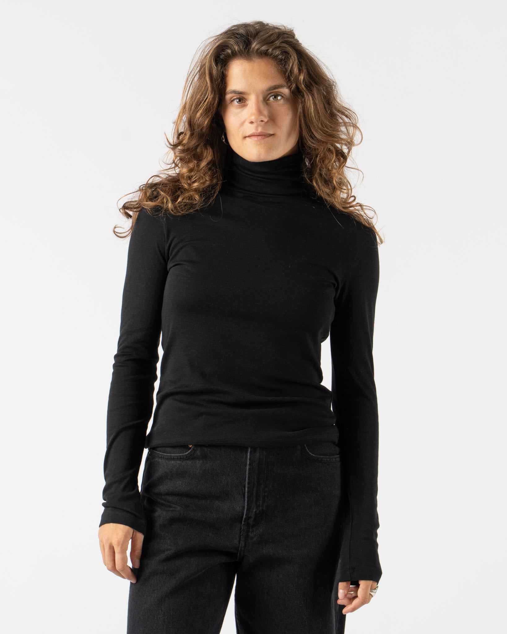 Woman wearing a black turtleneck and black pants on a white background