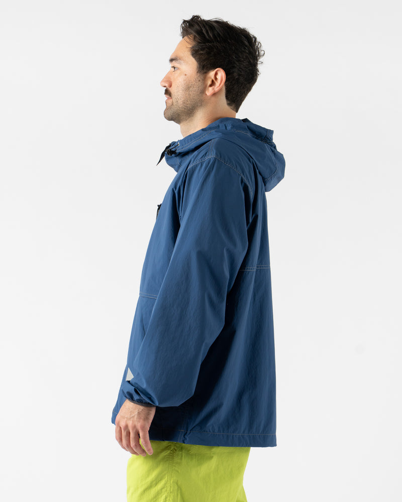Gramicci x and wander Brushed Nylon Jacket in Blue shown in various angles, featuring lightweight water-repellent nylon, reflective stitching, zippered pockets, and an oversized fit designed for both outdoor performance and urban style. Highlighting articulated sleeves, stand collar, and technical construction in a sleek matte blue finish.