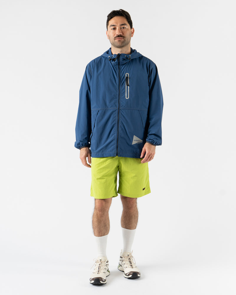 Gramicci x and wander Brushed Nylon Jacket in Blue shown in various angles, featuring lightweight water-repellent nylon, reflective stitching, zippered pockets, and an oversized fit designed for both outdoor performance and urban style. Highlighting articulated sleeves, stand collar, and technical construction in a sleek matte blue finish.