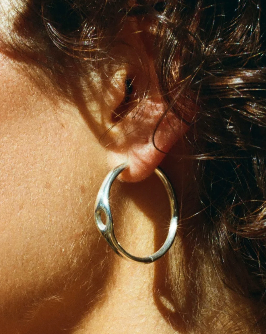 Close-up of a person wearing a silver hoop earring.