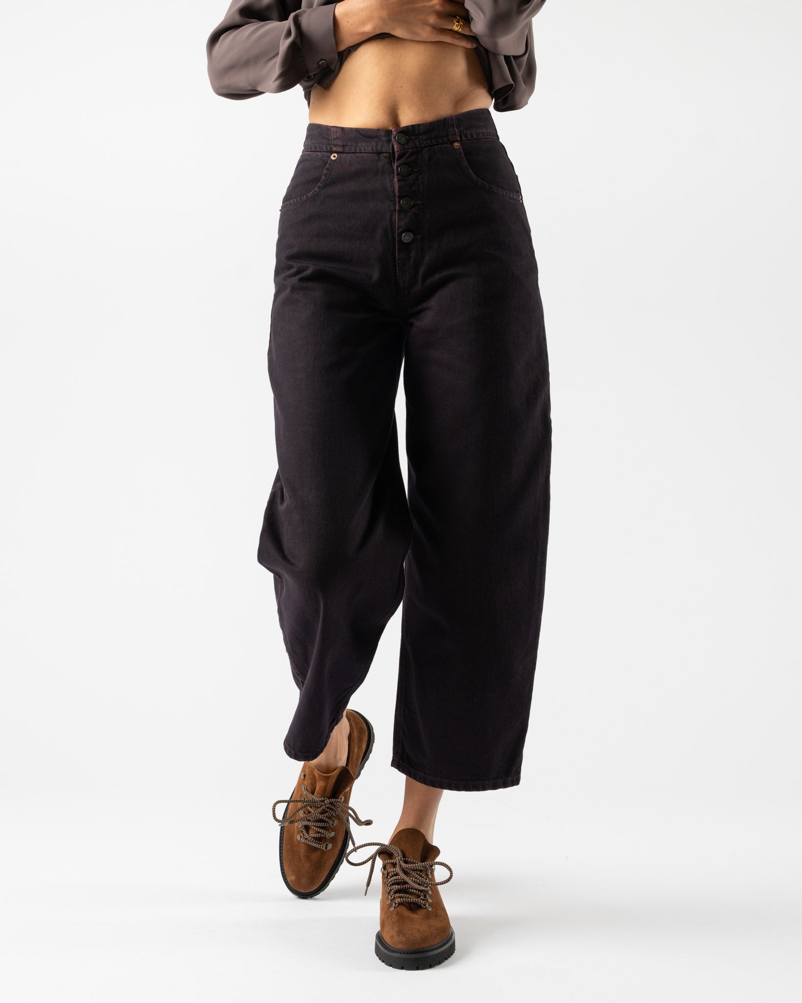 Person wearing black wide-leg pants and brown shoes on a white background